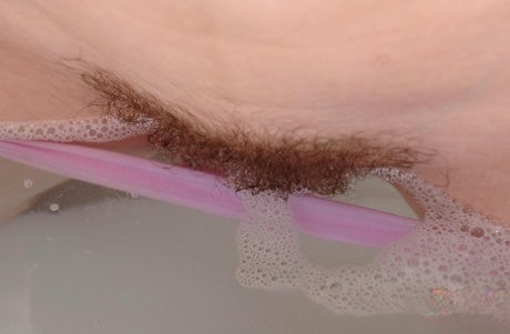 Natural redhead Denisa plunges her hairy vagina into a bathtub full of water
