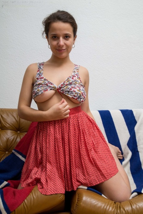 Busty amateur reveals her natural bush as she gets naked on a chesterfield
